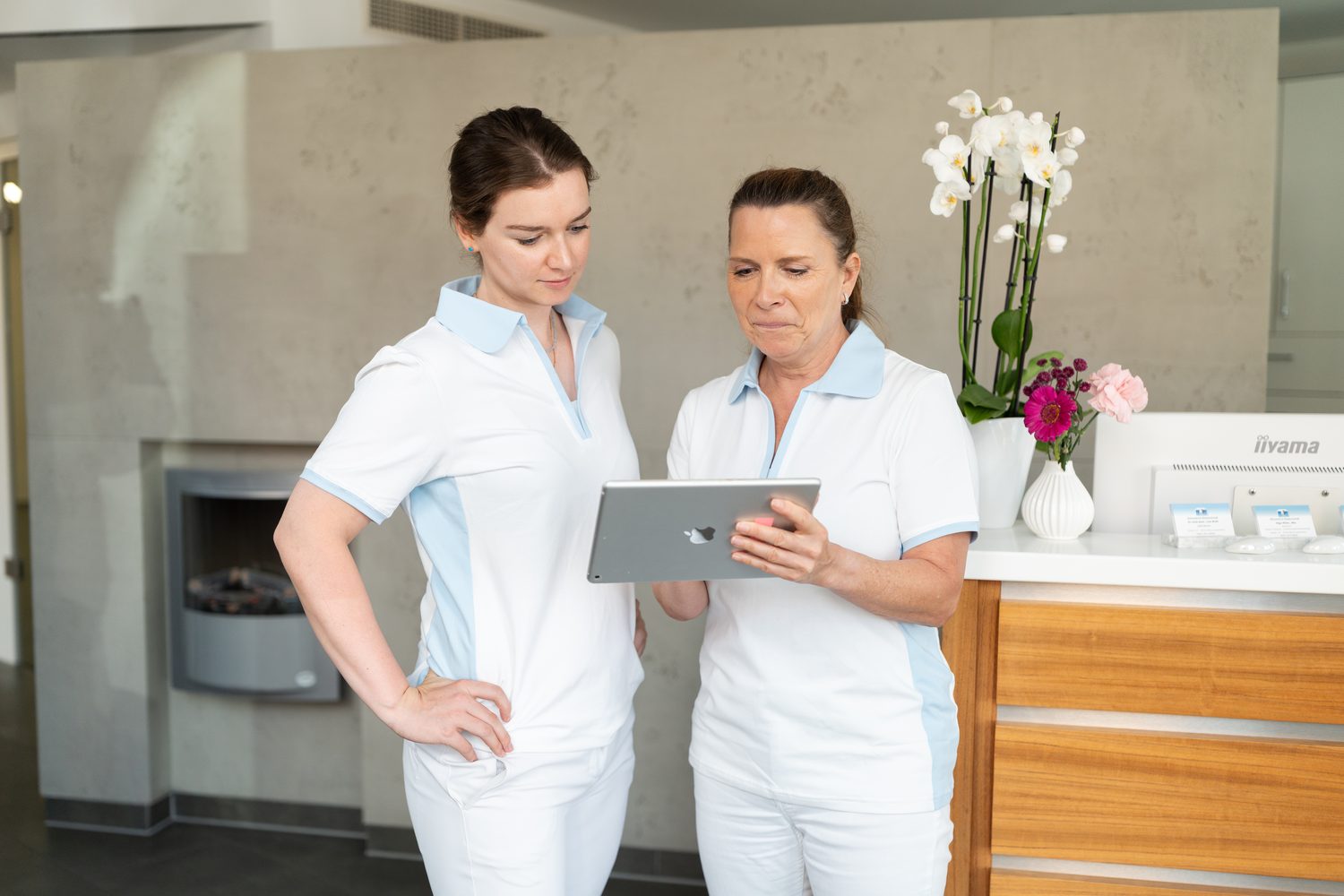 Zwei Kolleginnen besprechen sich am Empfang mit dem Tablet